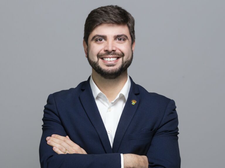 Felipe Camozzato, que propõe a isenção da taxa CDO para o arroz de exportação, sorrindo, de braços cruzados em um fundo cinza.
