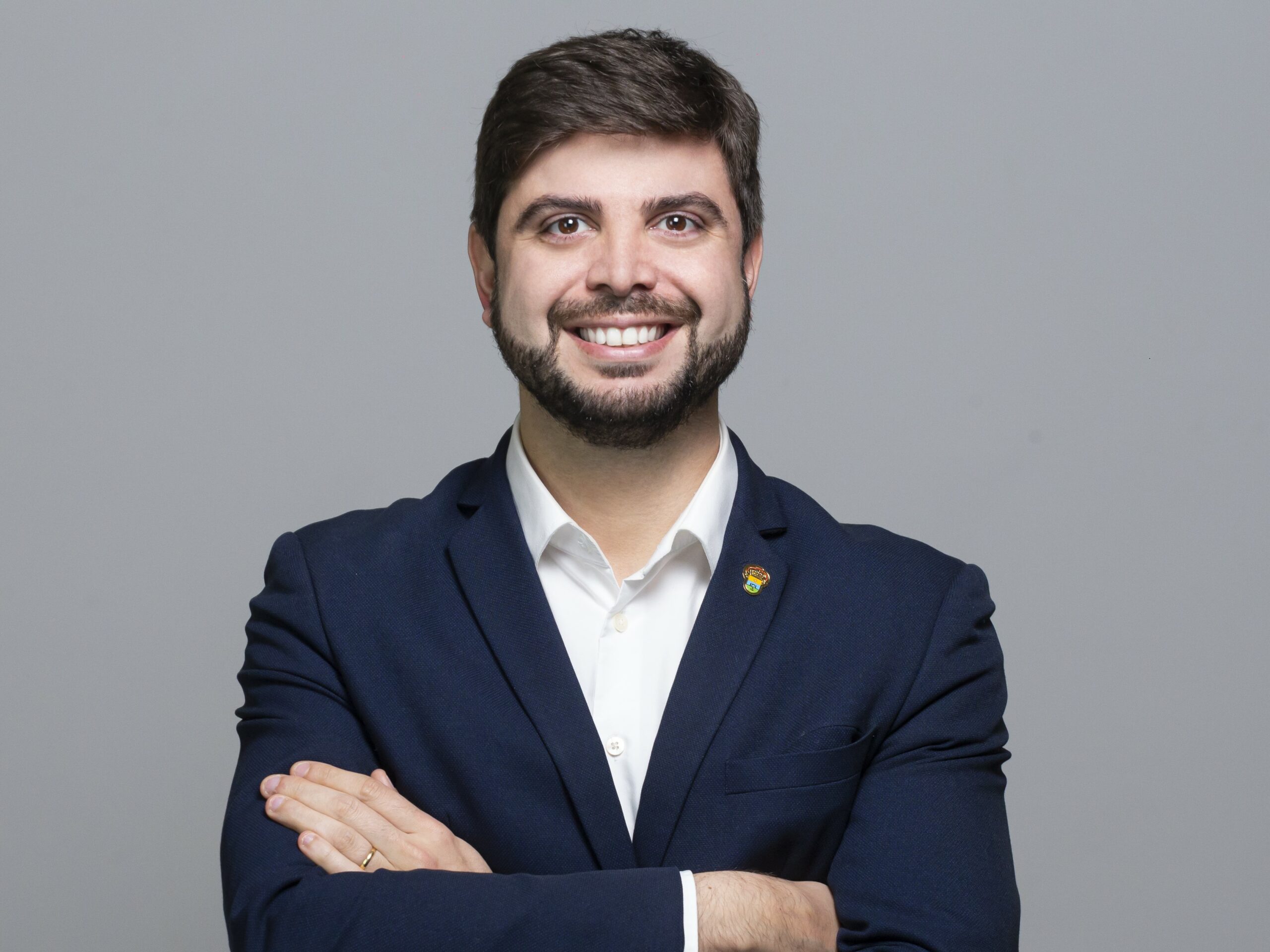 Felipe Camozzato, que propõe a isenção da taxa CDO para o arroz de exportação, sorrindo, de braços cruzados em um fundo cinza.
