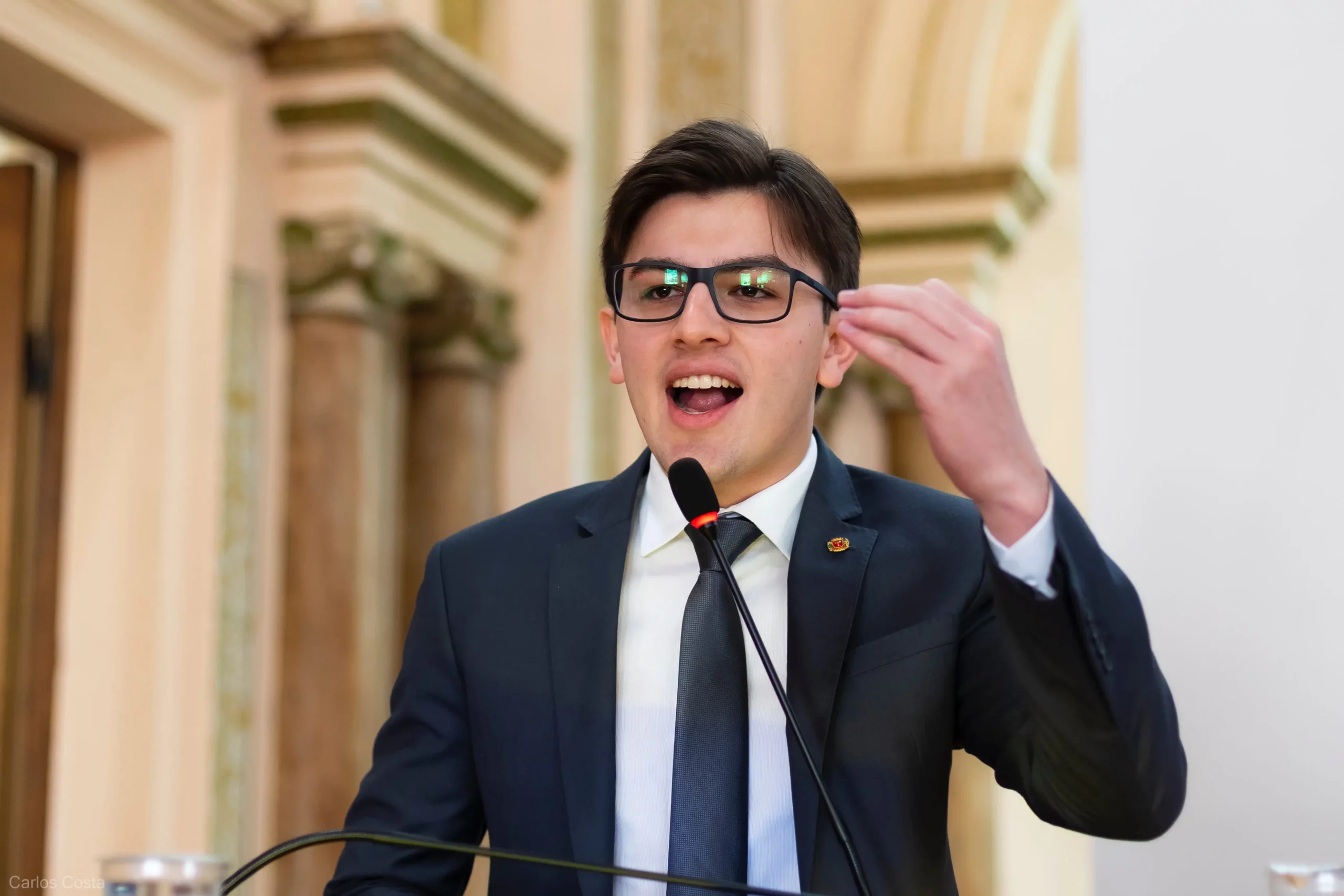 O vereador do NOVO, Guilherme Kilter, que apresentou um projeto para aumentar as punições contra pichação e vandalismo em Curitiba, aparece de pé discursando na tribuna da Câmara.