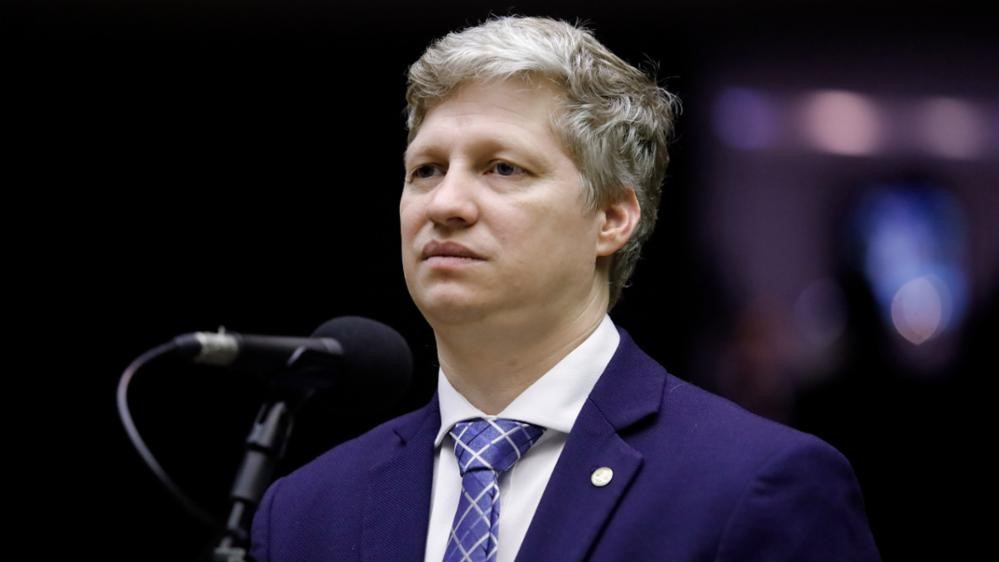 Na imagem da matéria “Câmara Pode Suspender Marcel van Hattem Nesta Terça”, Marcel aparece no plenário da Câmara dos Deputados.